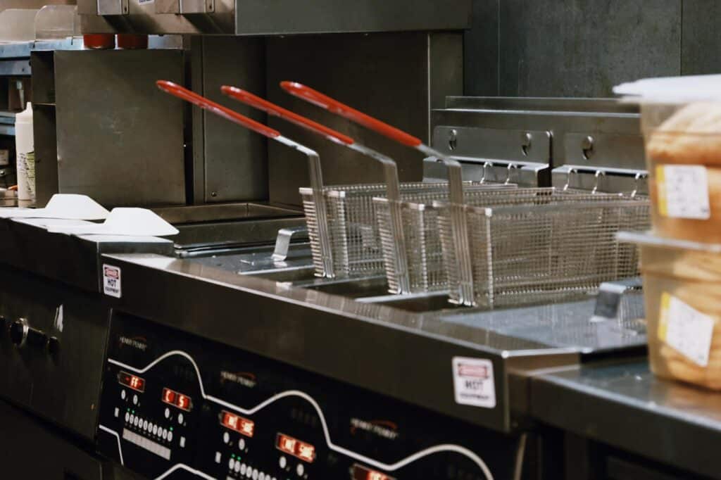 Commercial kitchen featuring multiple fryers, stainless steel countertops, and professional-grade cooking equipment.